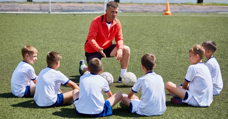 Entrenador trabajando con niños en un entrenamiento de fútbol